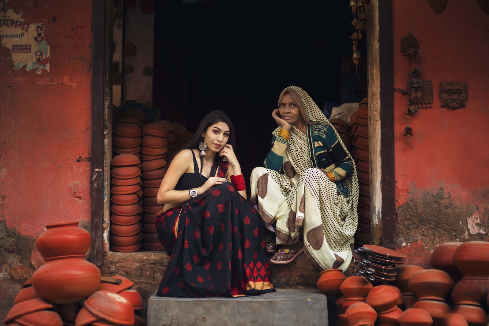 Women rights in India - Woman in Black and Red Dress Sitting Beside Old Woman Surrounded With Pots